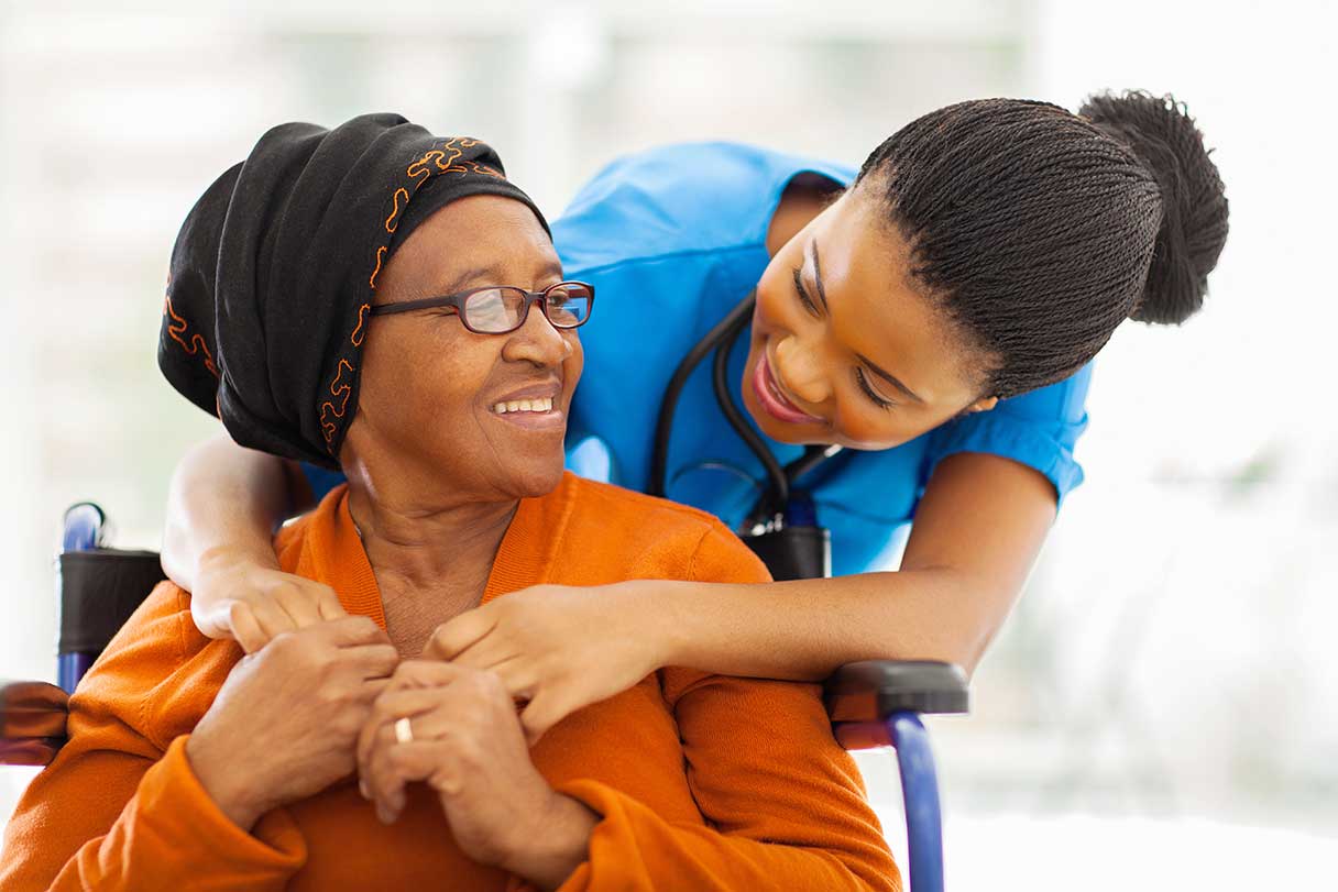 Nurse with her arms around a senior woman's shoulders