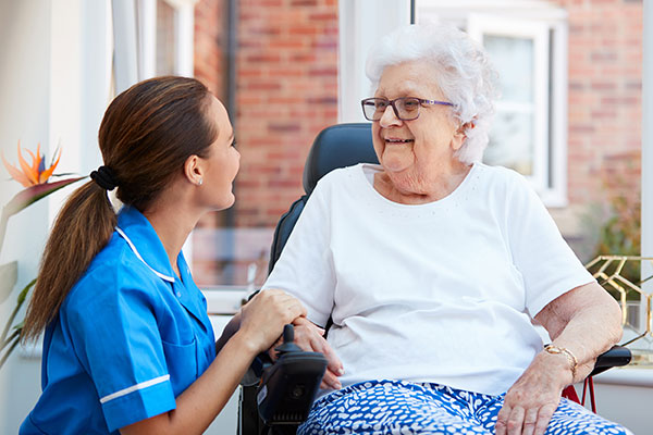 Woman kneeling next to a senior woman in a motorized wheelchair