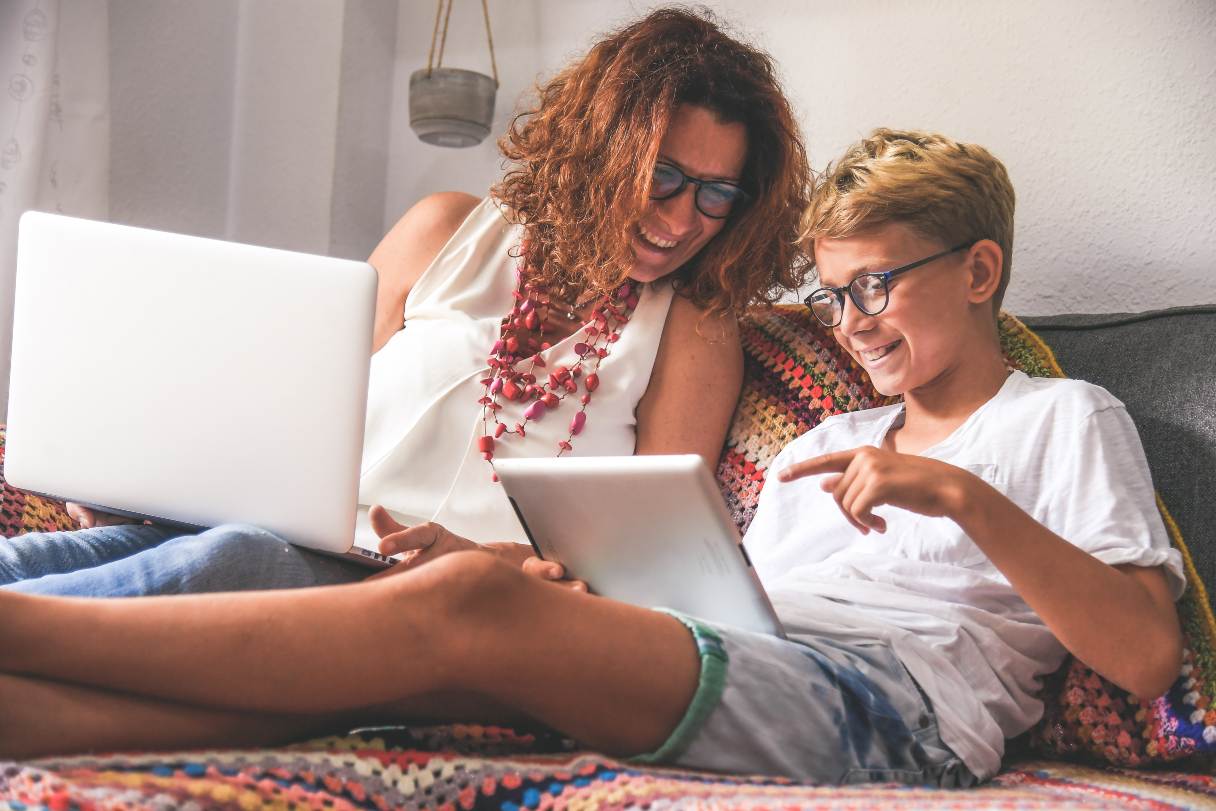 Mother and child working on laptops, both wearing glasses