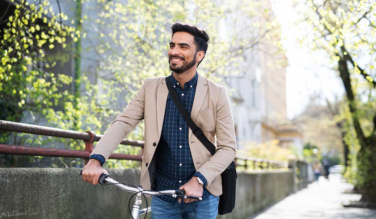 Smiling man walking his bike outside