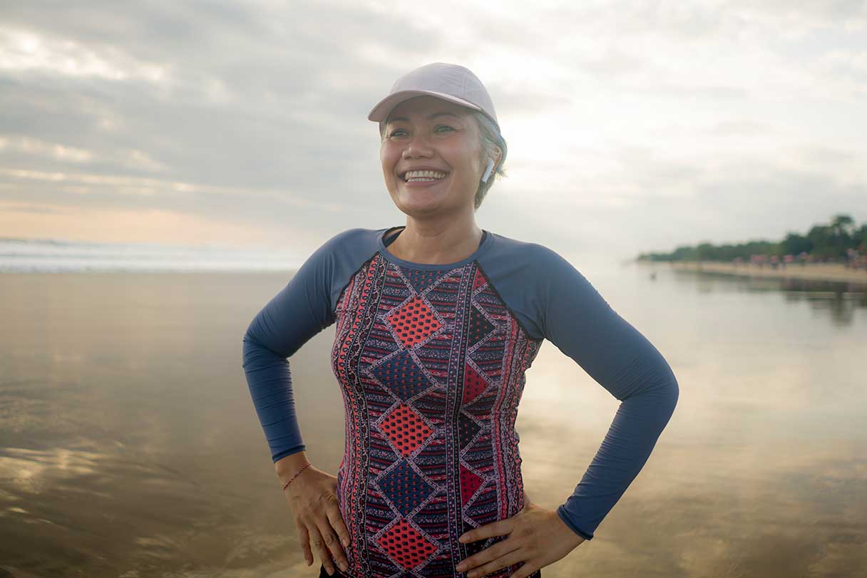 Woman in athleticwear, smiling on beach