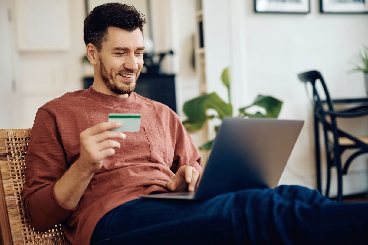 Man holding credit card while looking at laptop screen