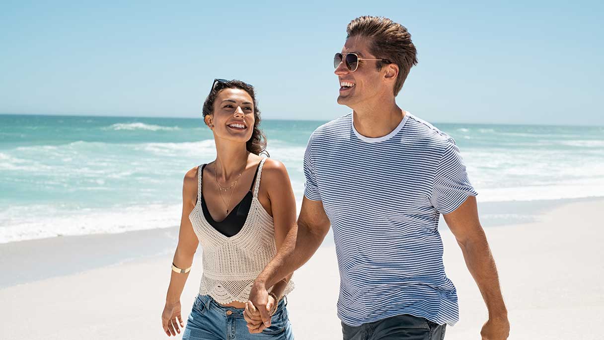 Couple holding hands, walking on beach