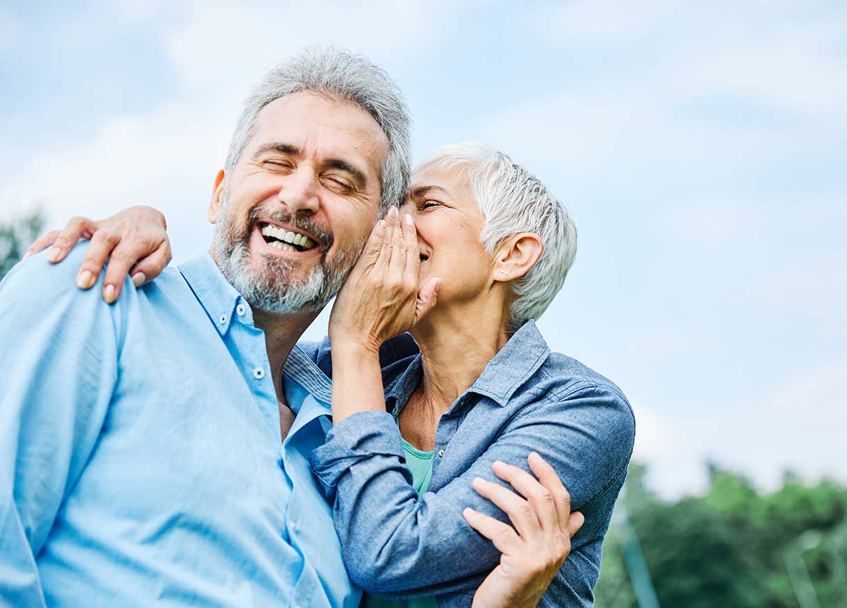 Senior woman whispering into a man's ear