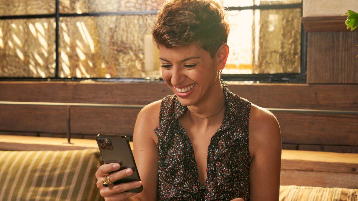 Woman smiling as she looks at her phone