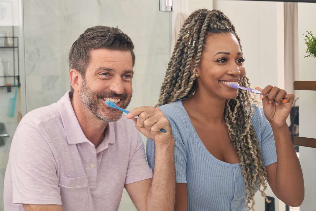 Man and woman brushing their teeth together