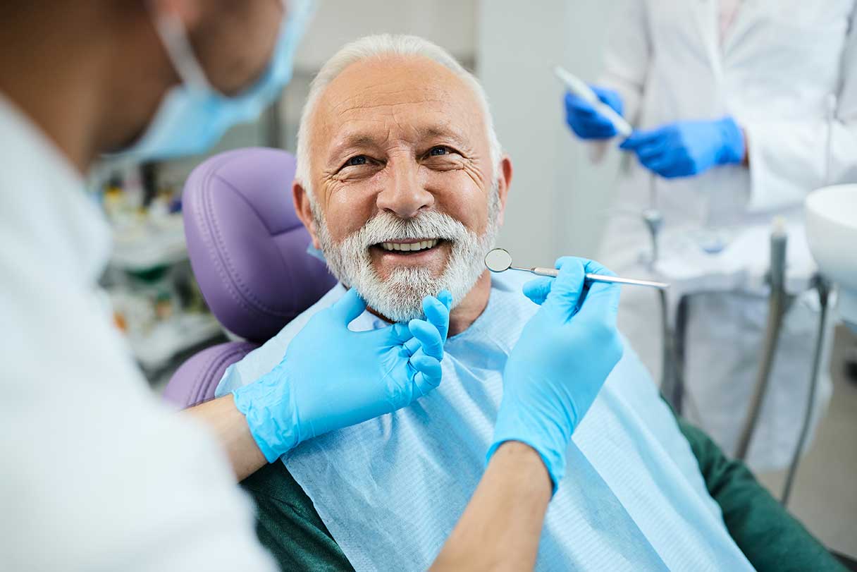 Woman in dental examination chair, looking at someone filling out a form on a clipboard