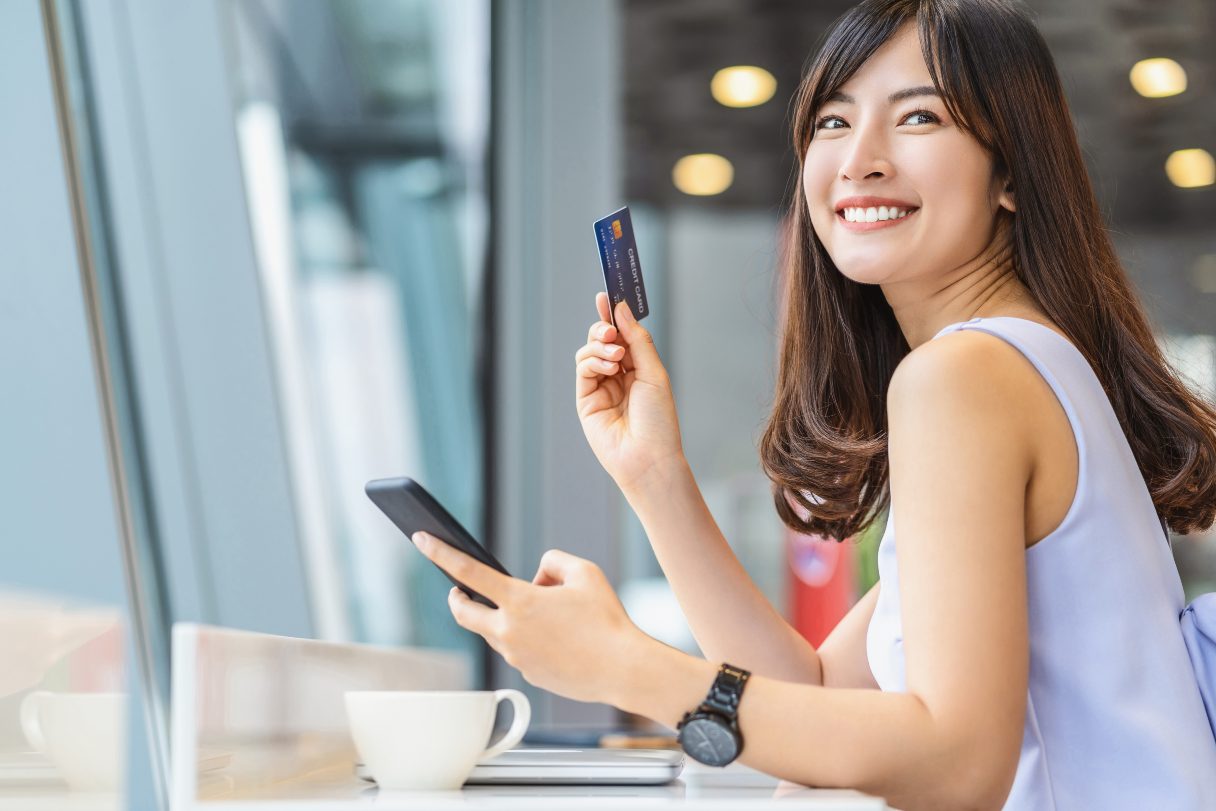 Smiling woman on her phone, holding a credit card