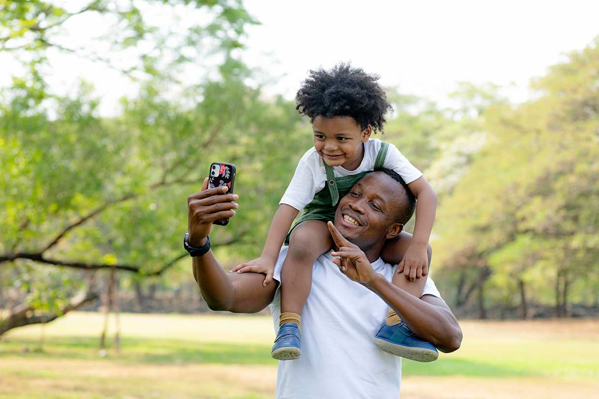 Man taking selfie with young boy on his shoulders