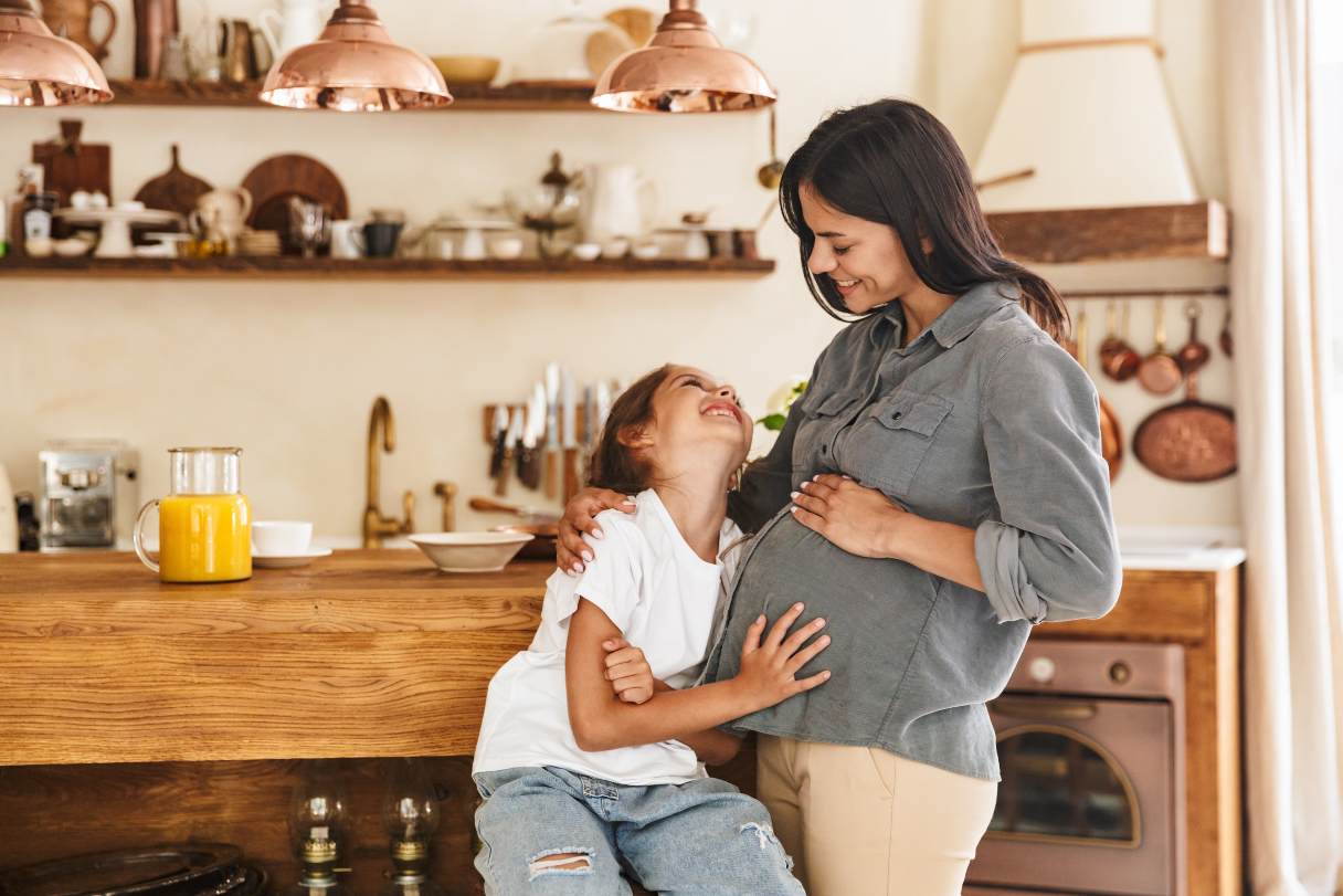 Little girl holding her mother's pregnant stomach