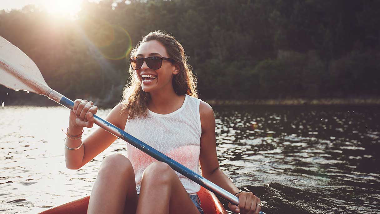 Woman in sunglasses, smiling as she kayaks