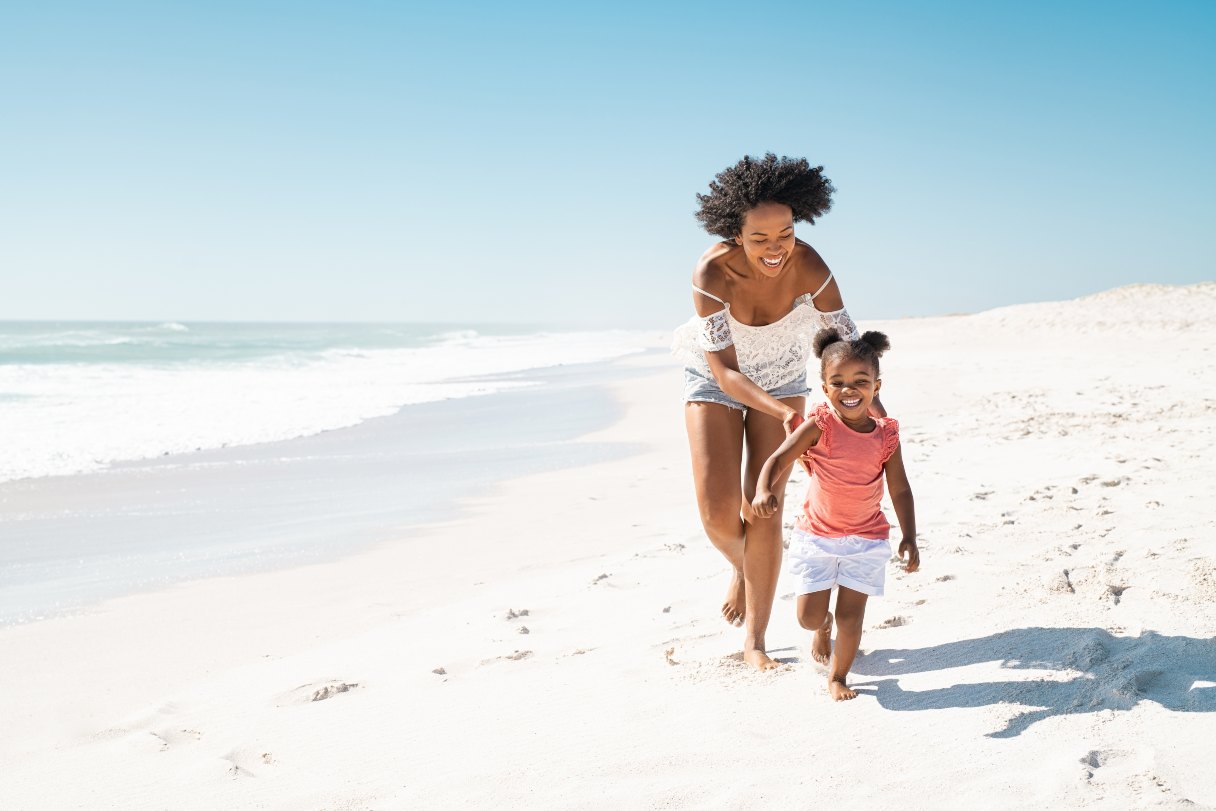 Woman walking with a young girl on the beach