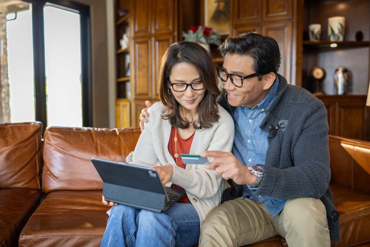 Man and woman, holding credit card, looking at laptop