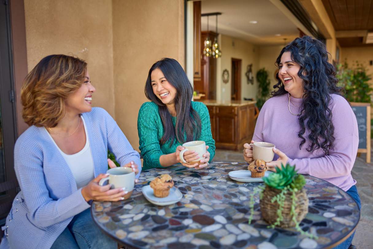3 women, sitting at a cafe and laughing together