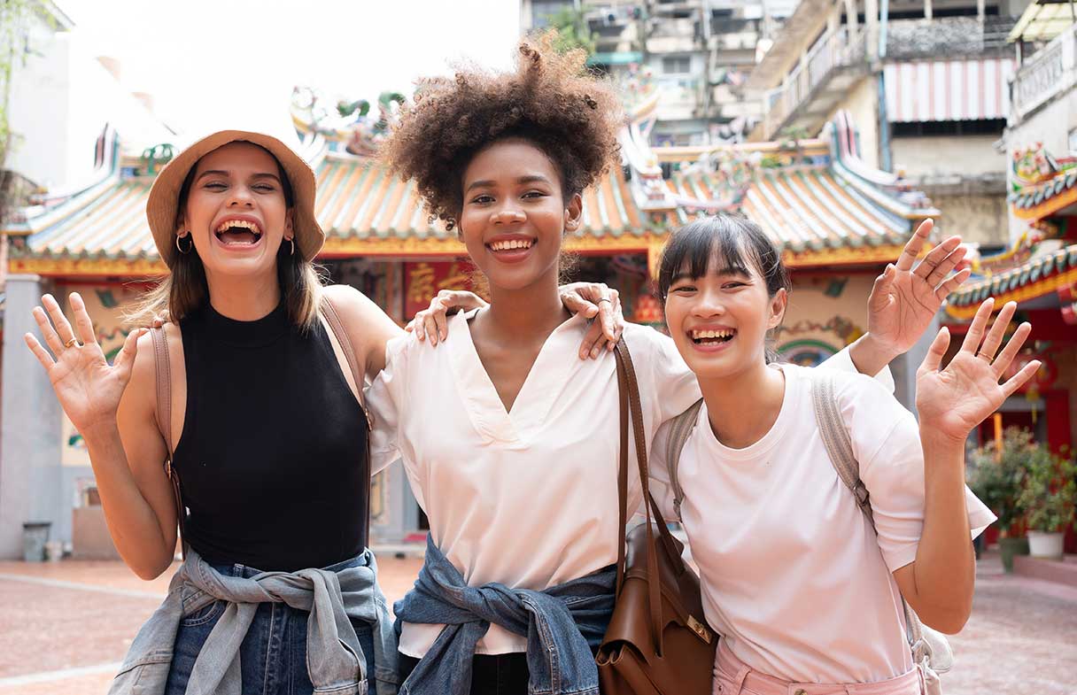 Three young tourist women outside, smiling