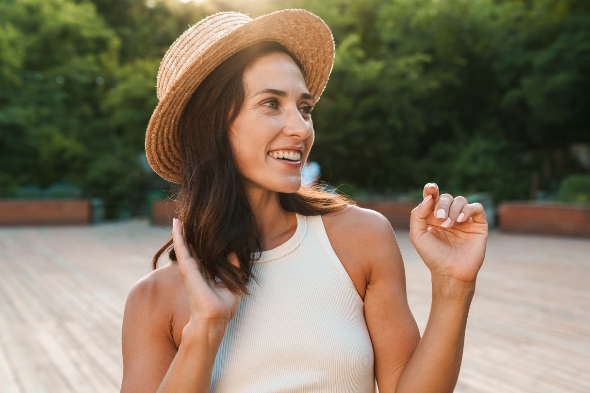 Smiling woman in hat standing outside