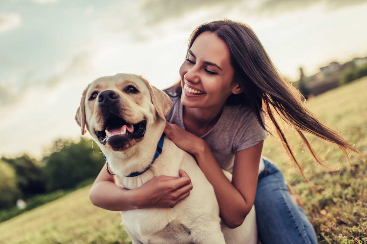 Smiling woman with her arm around labrador retriever