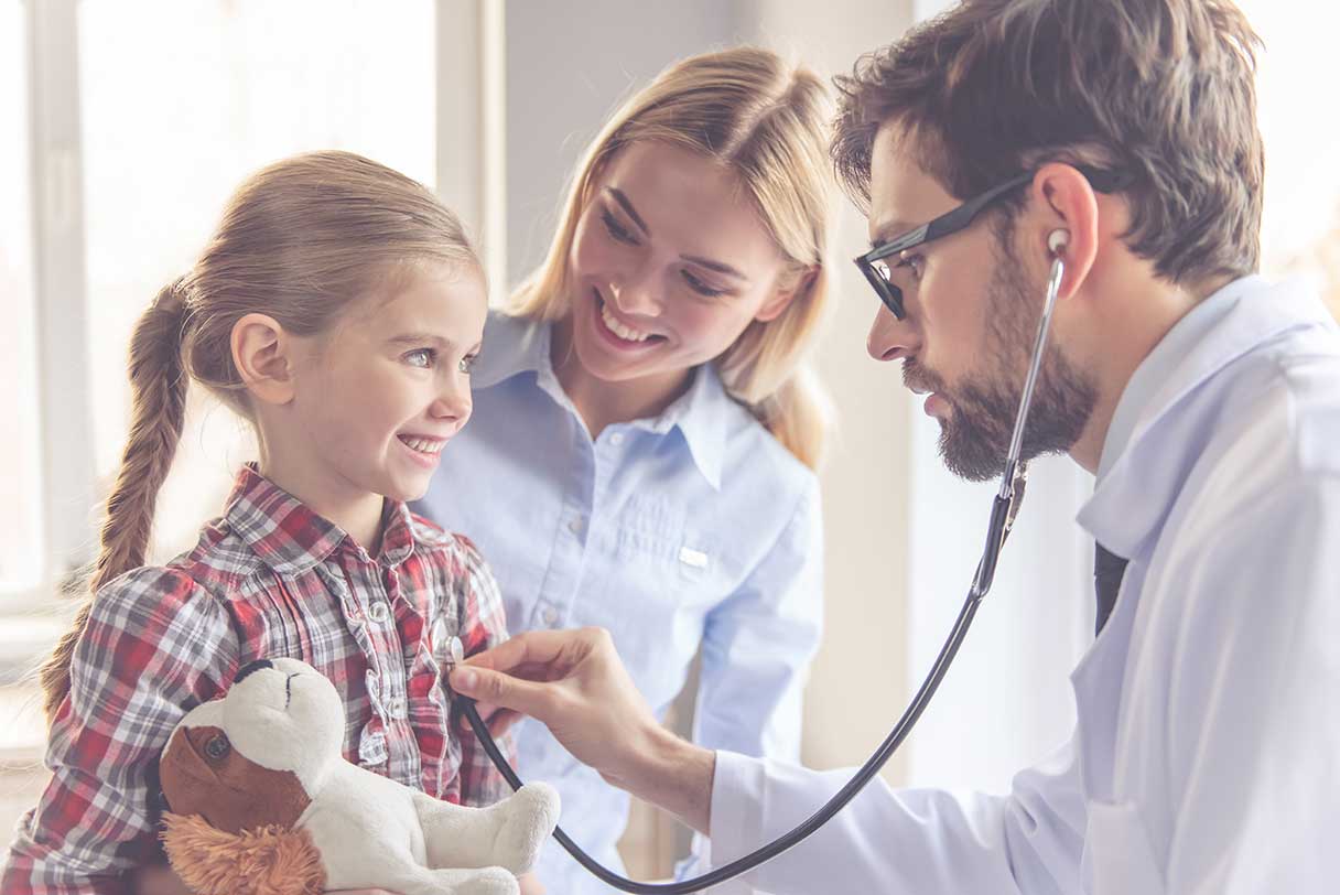 Doctor holding stethoscope to young girl's chest