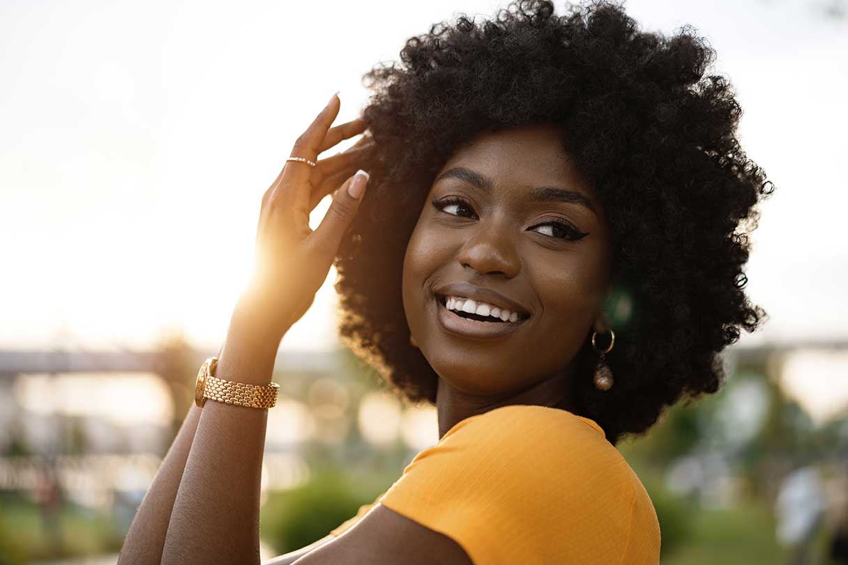 Woman in yellow shirt outside, smiling