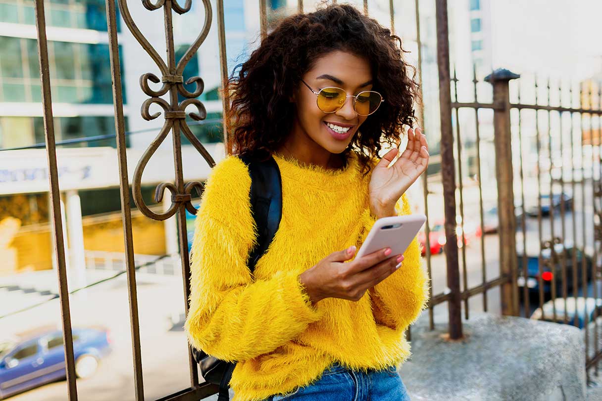 Smiling woman looking at her phone outside