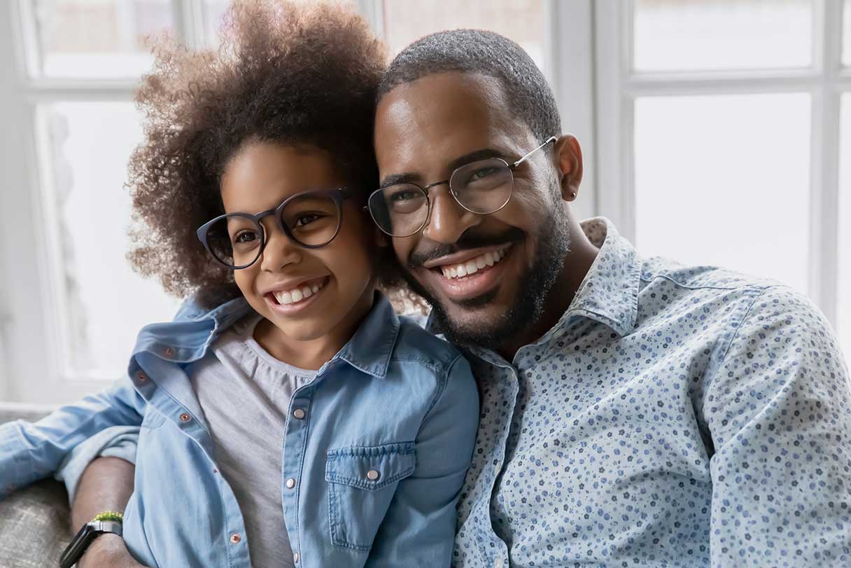 Man and small girl smiling, both wearing glasses