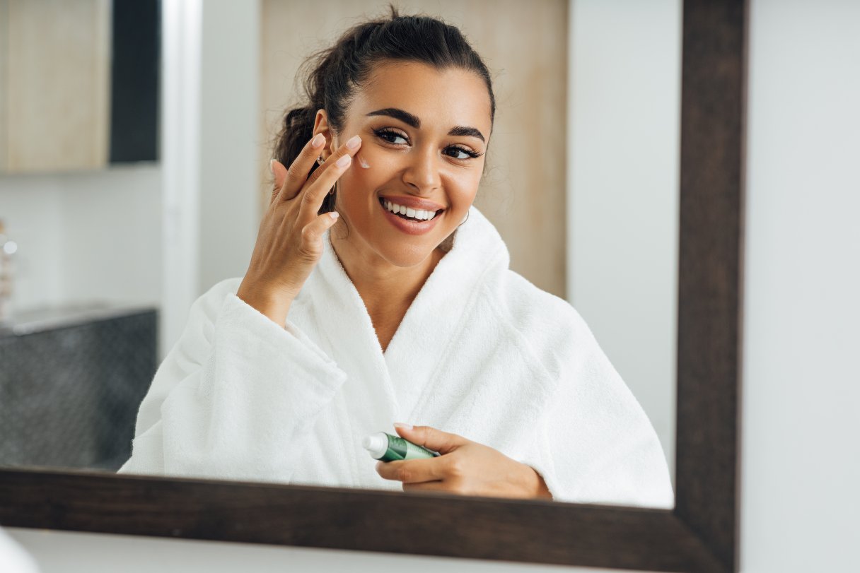 Woman applying cream to her face