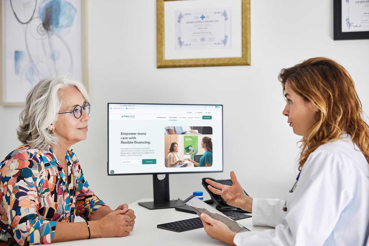 Healthcare professional speaking with patient in front of a computer monitor