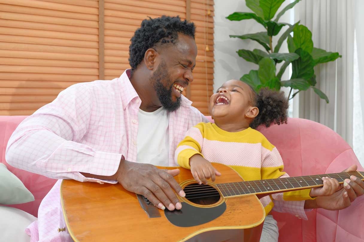 Man and young girl playing guitar