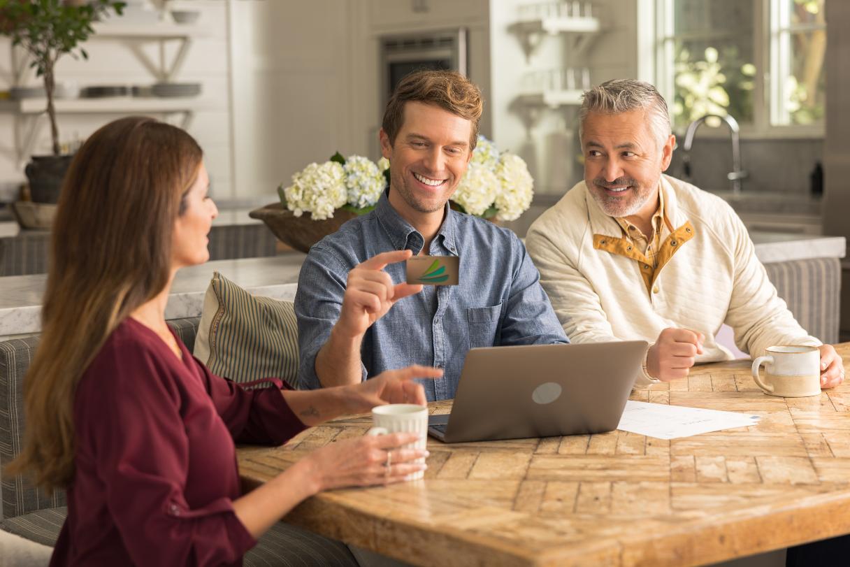 Three people sitting at table, looking at CareCredit credit card
