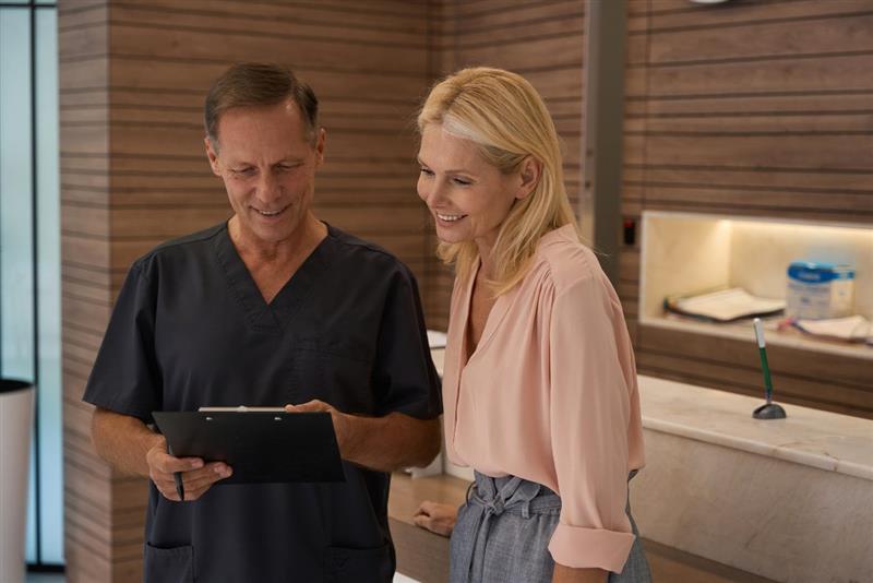 Man in scrubs showing a woman a clipboard