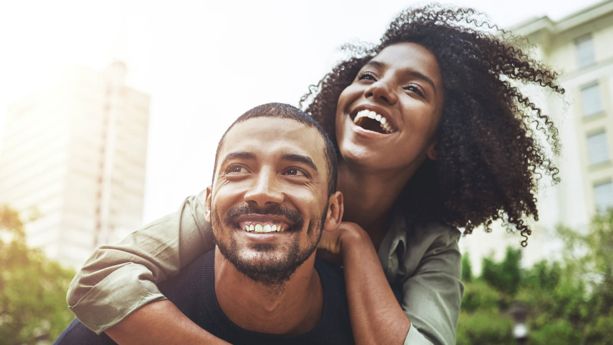 Man with woman on his back, both smiling