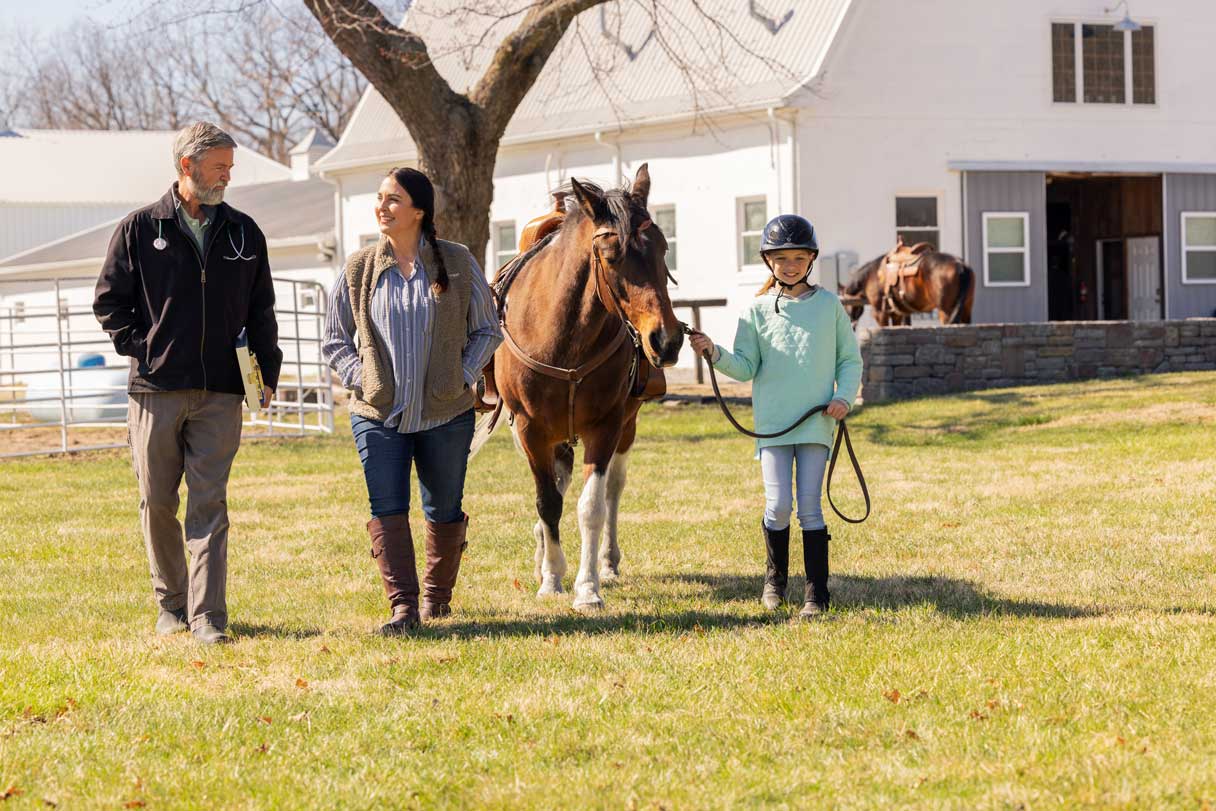 Man, woman and young girl walking with a horse